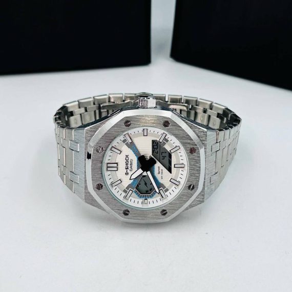 Relógio Gshock 1 Linha Diamante GM 2100 (M1) Prata no Atacado - Pulseira de Aço O Relógio Gshock 1 Linha Diamante GM 2100 (M1) Prata no Atacado é a escolha ideal para quem busca elegância, resistência e design sofisticado. Perfeito para revendedores que desejam oferecer um produto moderno, durável e com excelente aceitação no mercado, este modelo combina acabamento premium em prata com funcionalidades completas. Especificações Técnicas do Gshock GM 2100 (M1) Prata Modelo: GM 2100 (M1) Funções: Analógico e Digital (data, hora, alarme e cronômetro) Tamanho da caixa: 45mm Peso: 156 gramas Cor da caixa: Prata Cor da pulseira: Prata Funcionamento: Bateria Qualidade do maquinário: Chinês Catraca: Fixa Material da caixa: Emborrachada Material da pulseira: Aço À prova d’água: Sim (uso diário, evitar água quente ou salgada) Por Que Escolher o Gshock GM 2100 (M1) Prata no Atacado? Design sofisticado e moderno, ideal para diversas ocasiões Acabamento premium em prata, transmitindo elegância e durabilidade Alta resistência e conforto no uso diário À prova d’água e acompanha caixa, pronto para revenda ou presente Ótima margem de lucro para revendedores e lojas online Conteúdo da Embalagem 1x Relógio Gshock GM 2100 (M1) Prata - Pulseira de Aço 1x Caixa de proteção (ideal para revendedores e presentes) Garantia Todos os Relógios Gshock GM 2100 (M1) possuem garantia de 2 meses no maquinário. Leia atentamente as regras de garantia abaixo e no rodapé do nosso site. Adquira Agora o Gshock GM 2100 (M1) Prata no Atacado Garanta já seu Gshock GM 2100 (M1) Prata no Atacado e ofereça aos seus clientes um produto elegante, resistente, à prova d’água e com caixa inclusa. Estoque limitado — aproveite para aumentar suas vendas com confiança e qualidade.